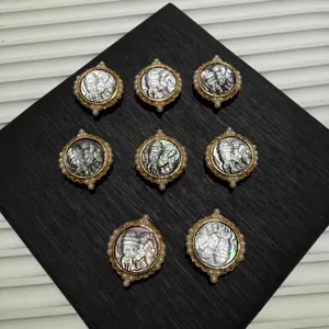 Detailed view of carved mother-of-pearl deity pendants with pearl inlaid gold frames.