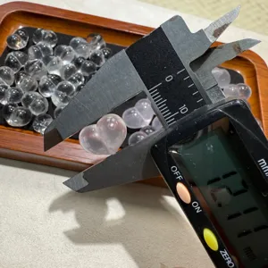 Close-up detail of natural white crystal heart bead being measured with a digital caliper.