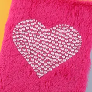 Gedetailleerde close-up van roze pluche notitieboekhoes met sprankelend kristallen strass hart.