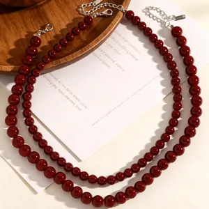 Détail du collier de perles en verre rouge foncé avec des perles polies et brillantes.