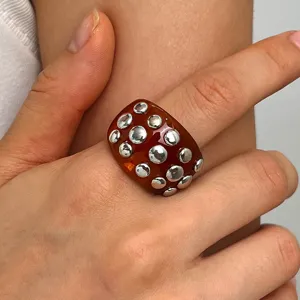 Chunky amber resin ring with metallic stud embellishments, punk retro fashion finger jewelry.