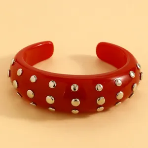 Red resin cuff bracelet with double rows of metal studs, punk style fashion detail view.