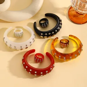 Close-up view of punk style resin bangles and matching rings with metal rivet decorations.