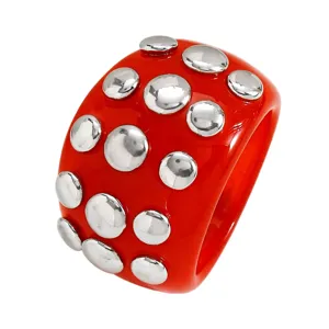 Close-up detail of the chunky resin ring featuring silver dome studs on a bright orange band.