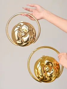 Golden metallic camellia flower relief spherical handbag with round handle detail showcase.
