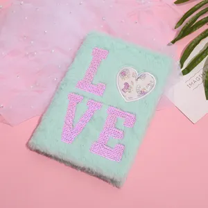 Détail de carnet pelucheux vert menthe mignon avec lettres LOVE en sequins roses.