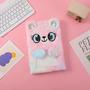 Dettaglio del quaderno in peluche rosa con occhi ricamati e orecchie arcobaleno soffici.