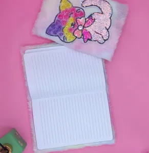 Close-up detail of the gradient tie-dye plush notebook with sequin unicorn motif.
