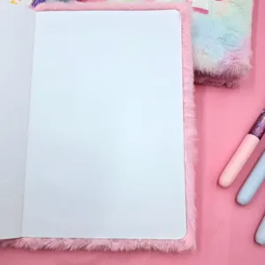 Close up of pink fluffy journal notebook open with blank white paper pages on pink background.