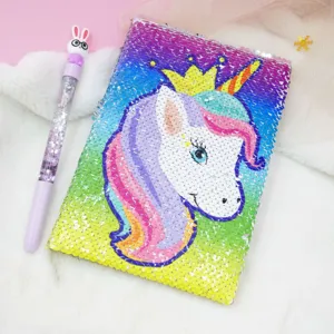 Close-up of a sparkling sequin unicorn notebook with a cute liquid glitter pen on fluffy background.