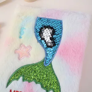 Détail de carnet en peluche coloré avec une broderie de queue de sirène en sequins.