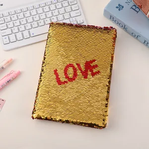 Detailed shot of a sparkly gold and red reversible sequin notebook with LOVE text.