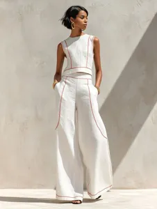 Detailed view of the white sleeveless top and wide-leg pants with stylish red contrast stitching.
