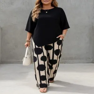 Completo taglie forti con top nero a maniche corte e pantaloni larghi fantasia.