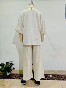 Back detail view of casual loose two-piece outfit with mid-sleeve top and wide-leg trousers in beige.
