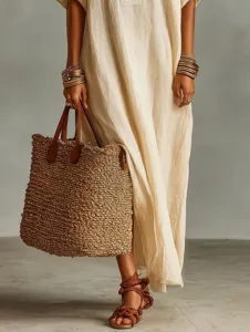 Elegant minimalist beige short sleeve dress detail with chic straw tote and metal bracelets.