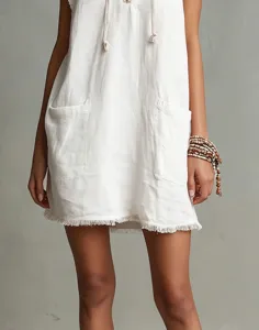 Detailed view of a white sleeveless mini dress featuring raw fringe hem and patch pockets.