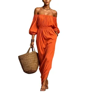 Schulterfreies gesmoktes orangefarbenes Maxikleid mit langen Ärmeln und Strohtasche.