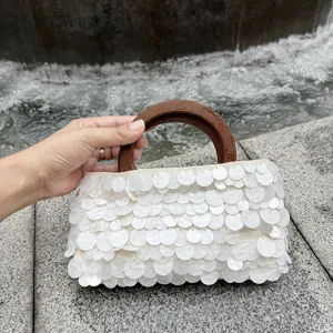 Gros plan détail d'un sac à main coquillage perlé style vintage français poignée bois.