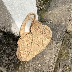 Nahaufnahme der handgehäkelten Blumen-Strohtasche in Khaki, ideal für Sommer-Looks.