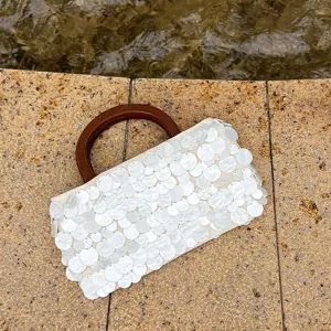 Sac à main blanc en sequins nacrés, vue détaillée montrant la texture perlée et la poignée bois.