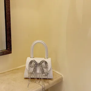 Kleine weisse Handtasche mit glitzernder Strass Schleife und feinen Quasten für Damen.