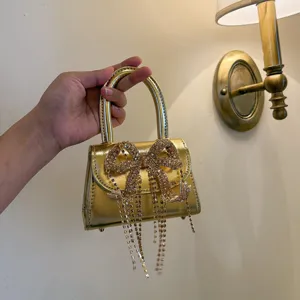 Elegante goldene Mini-Handtasche mit funkelnder Strass-Schleife und zarten Fransen.