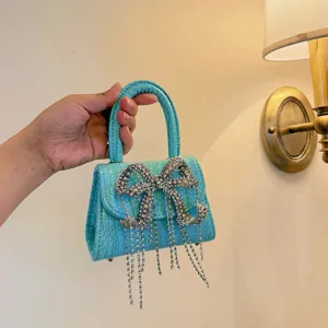 Detailaufnahme einer hellblauen geprägten Handtasche mit funkelnder Kristallschleife.