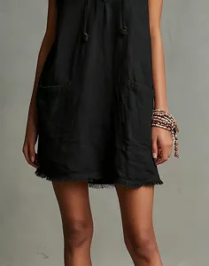 Black sleeveless mini dress detail showcasing V-neck, front pockets and stylish fringe hem.