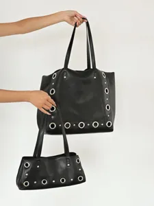 Detail view of black PU leather tote bag featuring metal grommets and rivets, chic shoulder bag.