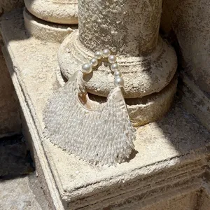 Nahaufnahme der eleganten, cremeweißen Perlen-Quasten-Handtasche mit Perlen-Tragegriff.