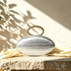 Detailed view of the chic oval evening clutch with luxurious metallic handle and textured finish.