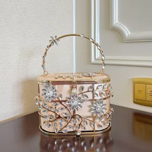 Détail exquis du sac de soirée à fleurs en strass, avec cadre métallique creux et fermoir perlé.