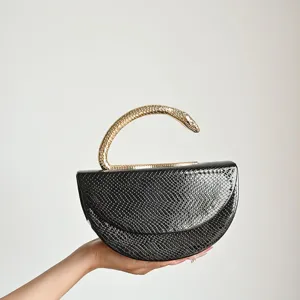 Detailed view of the black snakeskin evening bag with a unique gold snake handle design.