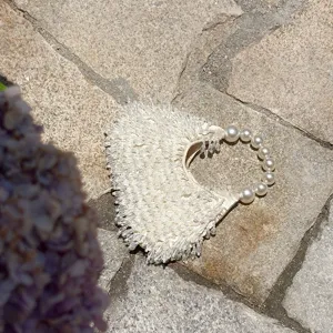 Detailaufnahme der eleganten cremeweißen Perlen-Fransen-Handtasche mit Perlenhenkel.
