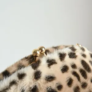 Nahaufnahme einer eleganten Vintage-Leopardenmuster-Plüschtasche mit goldenem Kuss-Verschluss.