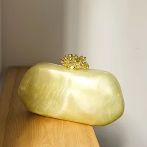 Resin Abendtasche Detail mit unregelmäßigem ovalen Körper und goldenem Korallenverschluss.