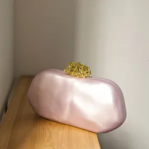 Exquisites Detail einer rosa unregelmässigen Abendtasche mit vergoldetem Korallenverschluss.