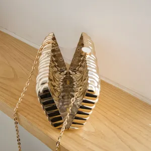 Gold metallic twisted texture hard shell clutch bag detail view, elegant evening purse design.
