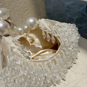 Elegante cremeweisse Perlen Abendtasche Detail mit funkelnden Kristallfransen und feinem Satin.