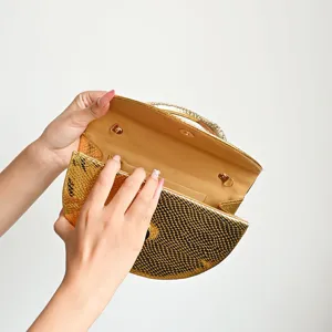 Detail view of gold snakeskin semi-circular evening clutch bag with rhinestone metal handle.