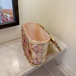 Vue détaillée du sac de soirée avec fleurs en cristal rose et fermoir perle sur marbre.