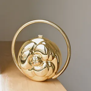 Golden camellia embossed round ball handbag with luxury circular handle for women fashion.