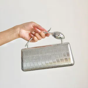Nahaufnahme Detail der silbernen Metallic Krokodilmuster Abendtasche mit speziellem Metallgriff.