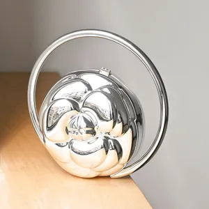 Silver metallic camellia flower embossed rigid evening clutch featuring a large round handle.
