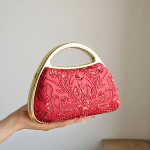 Borsa da sera ricamata rossa con fiori di perline e manico in metallo dorato elegante.