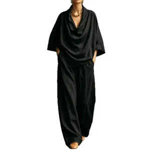 Detail view of black loose cowl neck top and wide leg trousers, elegant draped fabric.