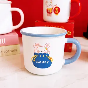 Jolie tasse en céramique avec motif de lapin et poignée bleue, idéale pour le lait et café.