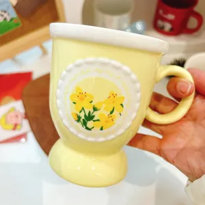 Chic yellow ceramic coffee mug with embossed floral pattern and elegant pedestal base for home.