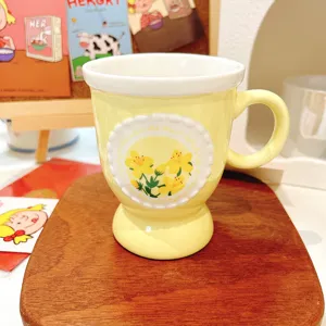 Detailed shot of yellow ceramic coffee mug featuring embossed floral pattern and elegant pedestal base.